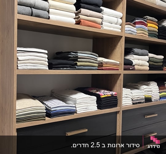 מדפים עם בגדים מקופלים בצבעים שונים בארון עץ